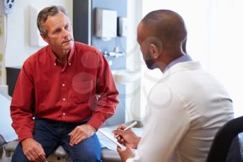 Male Patient And Doctor Have Consultation In Hospital Room