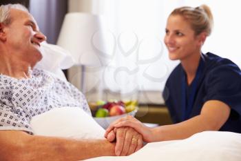 Nurse Talking To Senior Male Patient In Hospital Bed