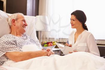 Female Doctor Talking To Senior Male Patient In Hospital Bed