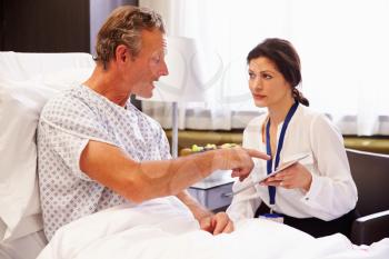 Female Doctor Talking To Male Patient In Hospital Bed