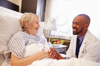 Doctor Talking To Senior Female Patient In Hospital Bed