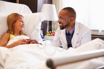 Doctor Talking To Child Patient In Hospital Bed