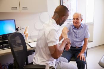 Senior Male Patient Working With Physiotherapist In Hospital