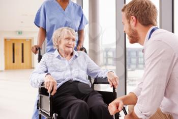 Doctor Talking To Senior Female Patient In Wheelchair