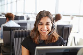 Young woman working in a call centre, looking to camera