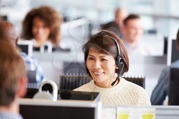 Asian woman working in call centre, surrounded by colleagues
