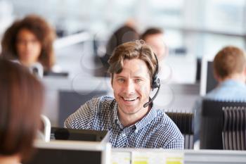 Young man working in call centre, looking to camera