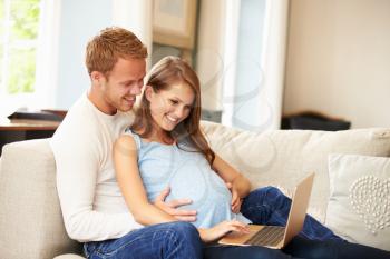 Couple With Pregnant Woman Using Laptop Computer Together