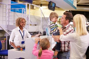 Family At Airport Check In Desk Leaving On Vacation