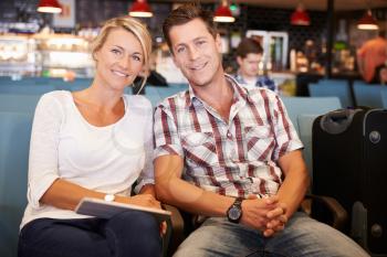 Couple In Airport Departure Lounge Waiting To Go On Vacation
