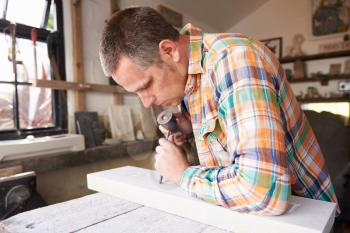 Stone Mason At Work On Carving In Studio