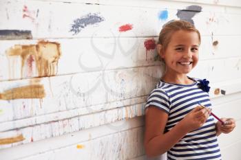 Portrait Of Girl Against Paint Covered Wall In Art Studio