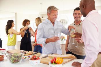Group Of Mature Friends Enjoying Dinner Party At Home