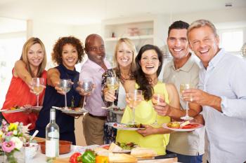 Portrait Of Mature Friends Enjoying Dinner Party At Home