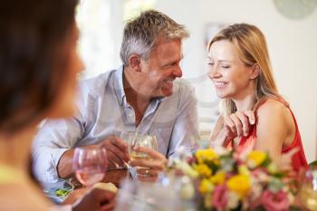 Mature Couple Sitting Around Table At Dinner Party