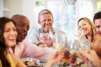 Mature Friends Sitting Around Table At Dinner Party