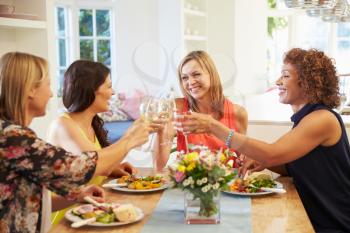 Mature Female Friends Sitting Around Table At Dinner Party