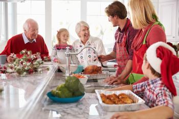 Extended Family Group Preparing Christmas Meal In Kitchen