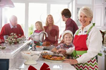 Extended Family Group Preparing Christmas Meal In Kitchen
