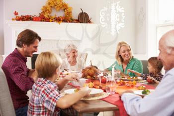 Family With Grandparents Enjoying Thanksgiving Meal At Table