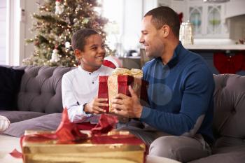 Father And Son Opening Christmas Presents At Home Together
