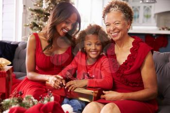 Girl With Grandmother And Mother Opening Christmas Gifts