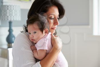 Loving Mother Holding Baby Daughter At Home