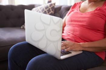 Close Up Of Senior Woman Sitting On Sofa Using Laptop
