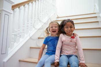 Portrait Of Two Girls Playing Game On Staircase At Home