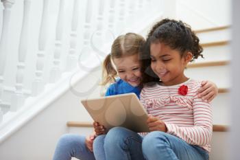 Two Girls Sitting On Staircase Using Digital Tablet