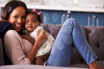 Portrait of woman relaxing at home with her toddler daughter