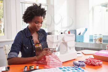 Young black woman stitching fabric using a sewing machine