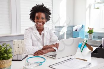 Female doctor in white coat looking to camera in an office