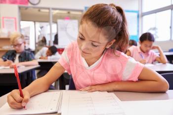 Schoolgirl writing at her desk in an elementary school class