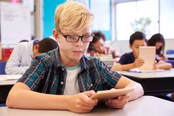Boy with glasses using tablet in elementary school class