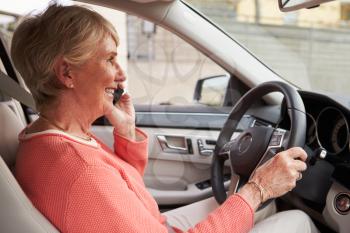 In car view of senior female driver speaking on her phone