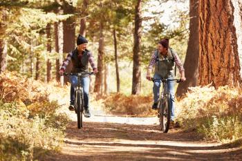 Couple mountain biking through forest, California
