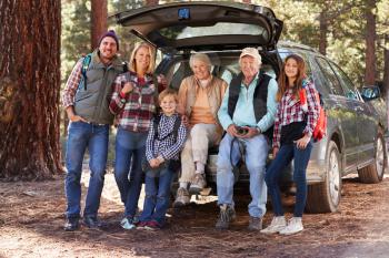 Multi generation family standing by a car before forest hike