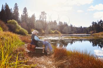 Senior man sits fishing, Bluff Lake, California