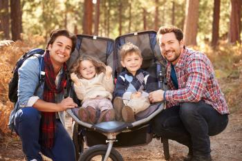 Gay Male Couple Pushing Children In Buggy Through Woods