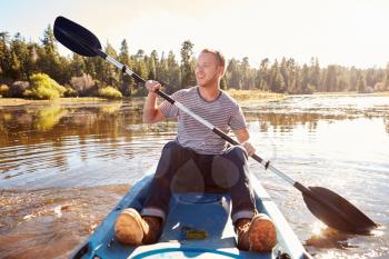 Young Man Rowing Kayak On Lake