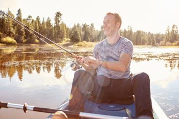 Young Man Fishing From Kayak On Lake