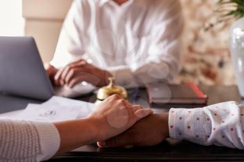 Multi ethnic couple hold hands at hotel check in desk, detail