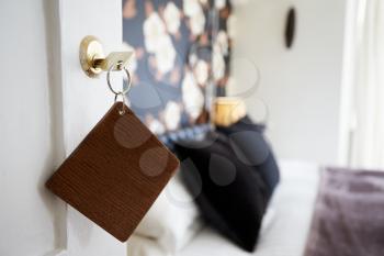 Key And Wooden Fob In Door Of Hotel Bedroom