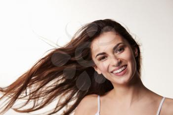 Dark haired, late teen girl, hair blowing, smiles to camera