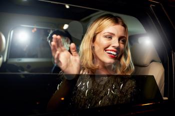 Glamorous woman waving through the window of a limousine