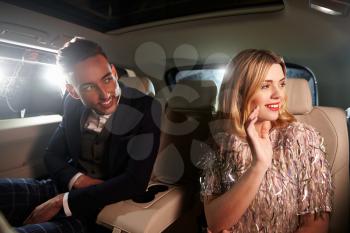 Attractive young couple laughing in the back of a limousine