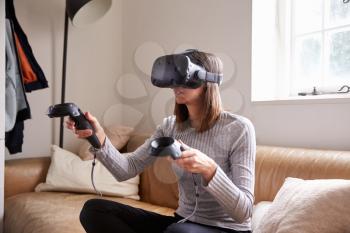 Woman At Home Wearing Virtual Reality Headset Playing Game