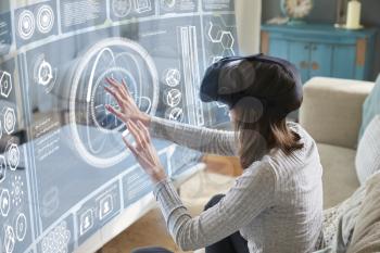 Woman Sits On Sofa At Home Wearing Virtual Reality Headset