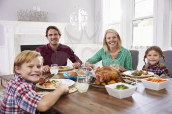 Portrait Of Family Sitting Around Table Eating Meal At Home